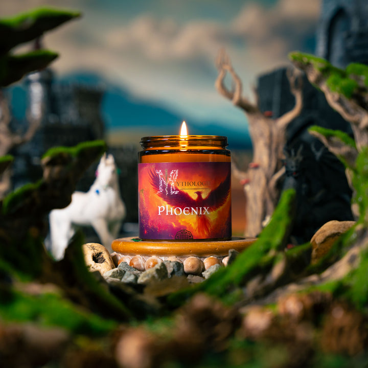 Candle labeled 'Phoenix' in a natural setting with plants and rocks.